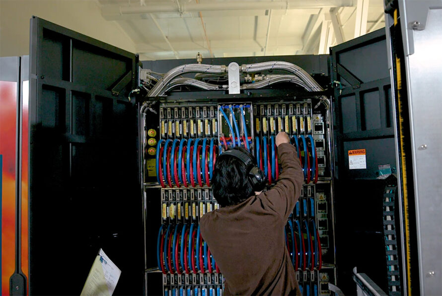 Person stands facing toward racks in a supercomputer